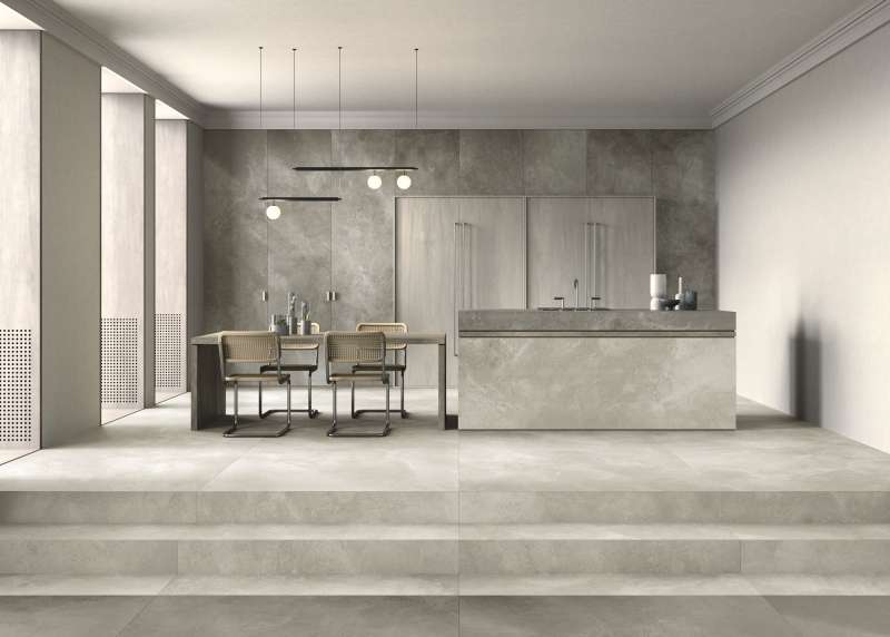 Großzügiger Wohnraum mit hochwertigen Fliesen: helle Bodenfliesen und graue Wandfliesen in Betonoptik.