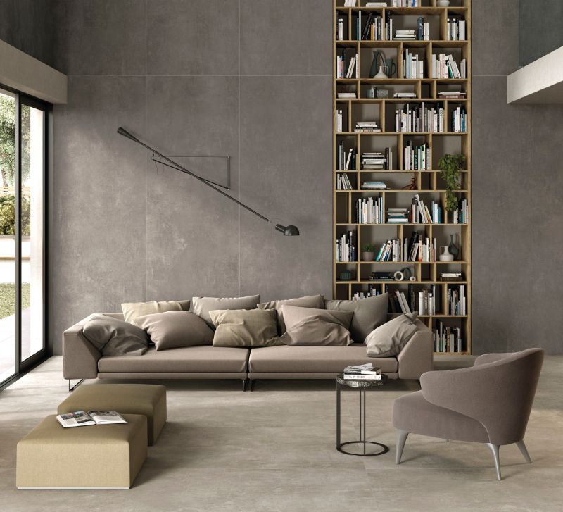 Modernes Wohnzimmer mit großformatigen Fliesen in Betonoptik an Wand und Boden.