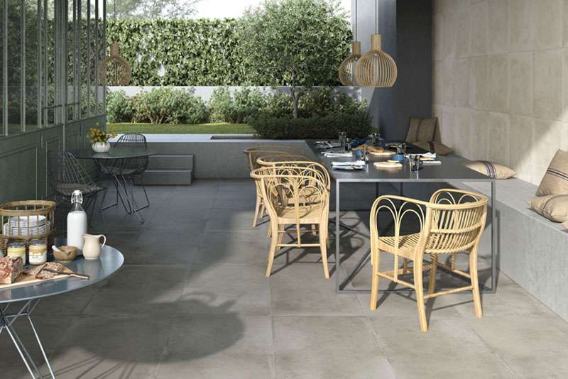 Moderne Outdoor-Fliesen in Dunkelgrau auf einer stilvollen Terrasse mit Essbereich und Garten.