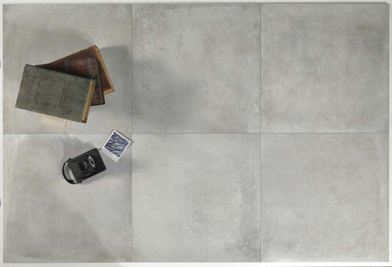 Großformatige graue Fliesen in Betonoptik, dekoriert mit Büchern und einer Kamera.