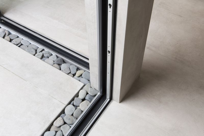 Helle Fliesen mit dekorativem Kiesstreifen am Übergang von Innen nach Außen.