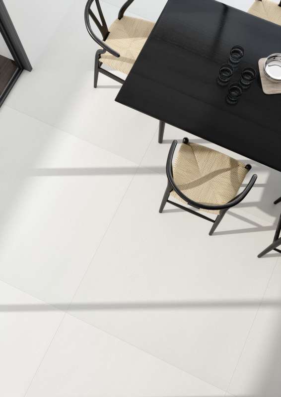 Helle, großformatige Bodenfliesen in einem modernen Essbereich mit dunklem Tisch.