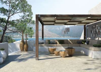 Stilvolle Outdoor-Terrasse mit hellen Fliesen, Pergola und Lounge-Bereich mit Meerblick.