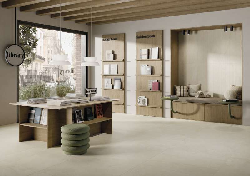 Moderner Loungebereich mit hellen, großformatigen Fliesen, Holzeinrichtung und Leseecke.