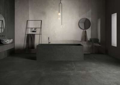 Modernes Badezimmer mit dunklen Fliesen an Boden und Wänden, Badewanne und Waschbecken.