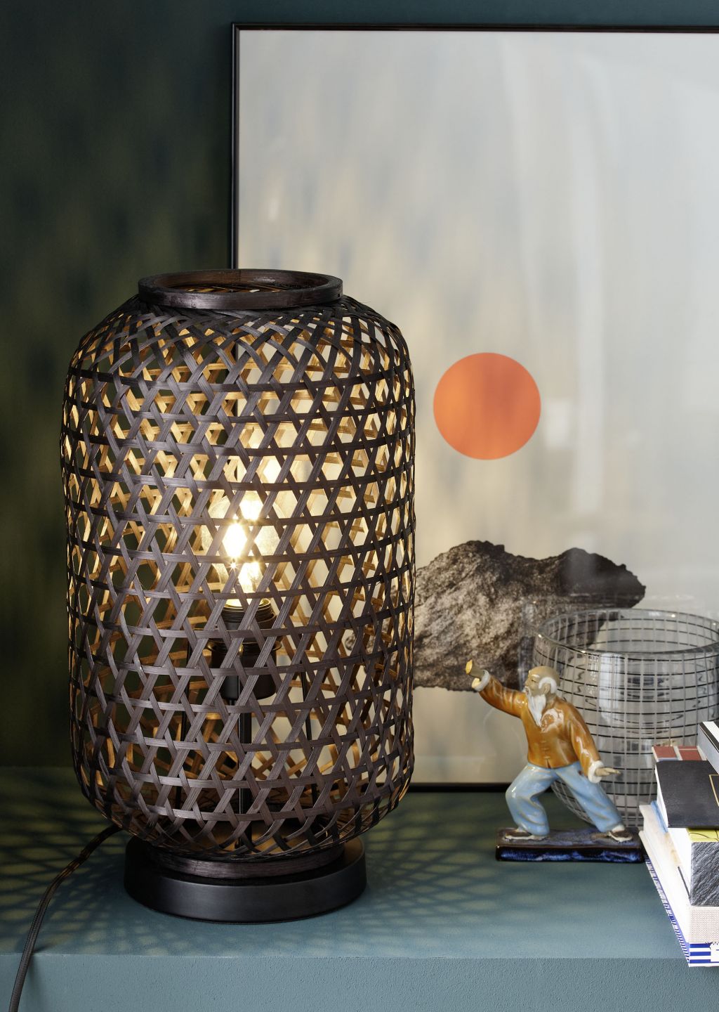 Stilvolle Dekorationsecke mit geflochtener Lampe und Kunst.