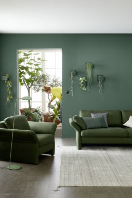 Stilvolles Wohnzimmer mit hellem Fliesenboden und dunkelgrünen Wänden.