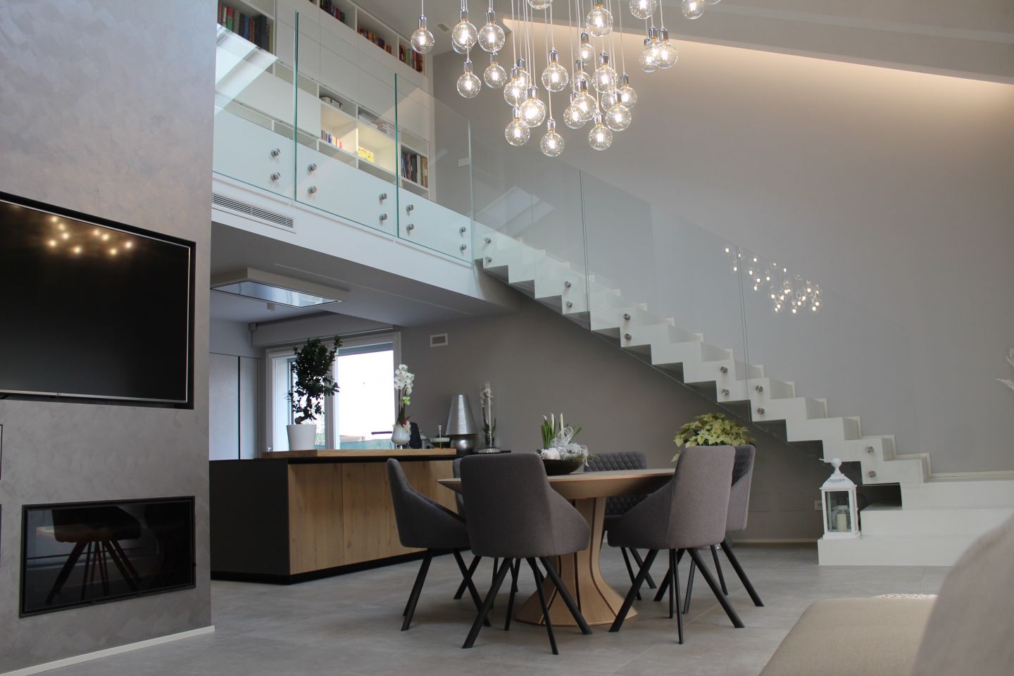 Moderner Wohnbereich mit großformatigen grauen Fliesen, Essplatz und offener Galerie.