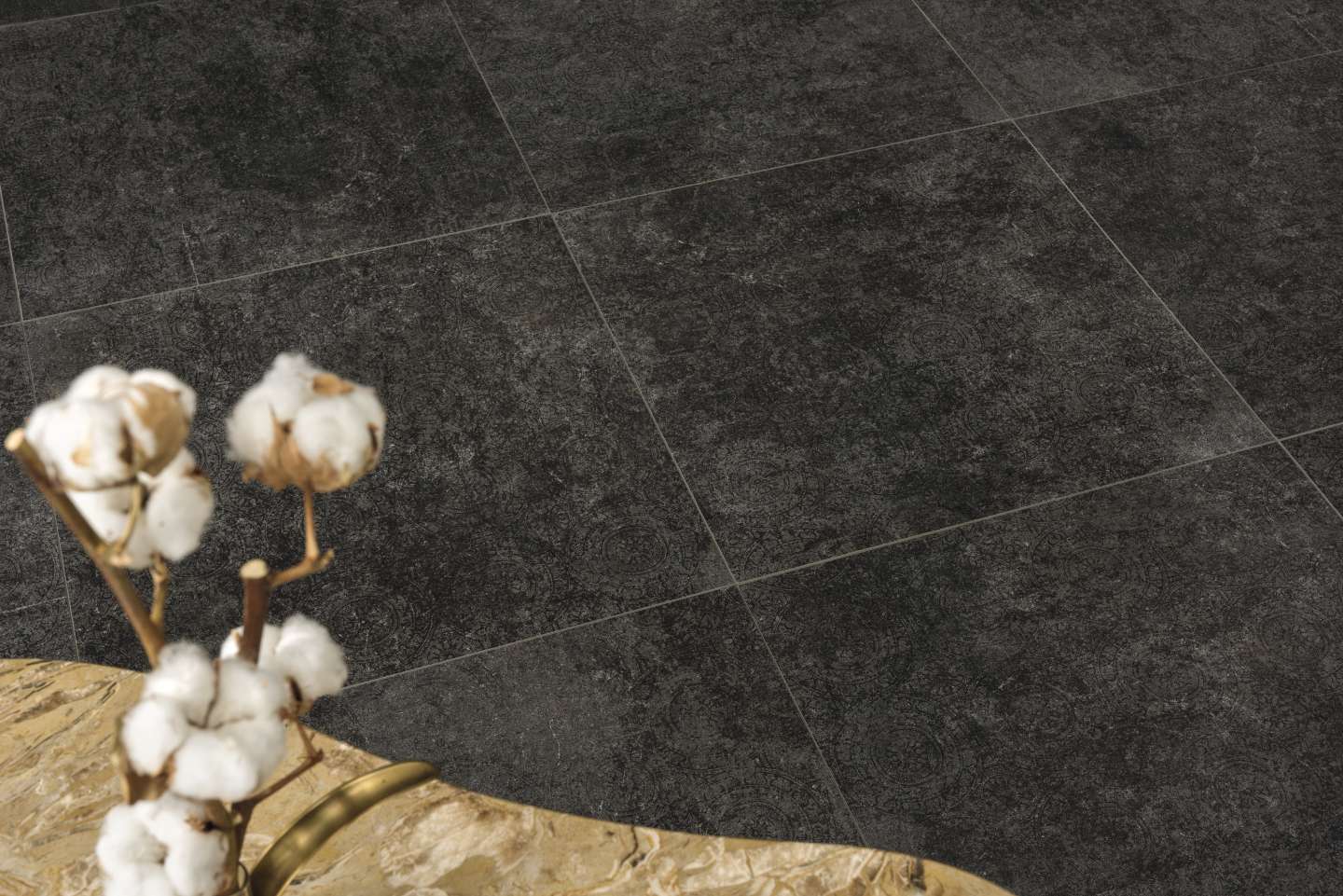Anthrazitfarbene Fliesen mit strukturierter Oberfläche und Baumwollzweig.