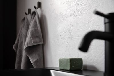 Strukturierte Wandfliese im modernen Bad mit Handtüchern und schwarzer Armatur.