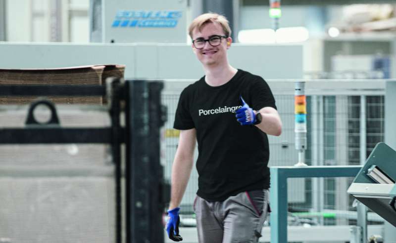 Ein lächelnder Mitarbeiter von Porcelaingres in der Fliesenproduktion zeigt Daumen hoch.