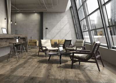 Loungebereich mit Porcelaingres Holzoptik-Fliesen und Beton-Look Wänden, ideal für moderne Innenräume.