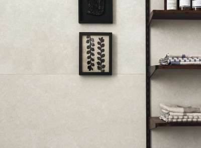 Helle, großformatige Wandfliesen in Betonoptik, stilvoll inszeniert mit Bildern und Regal.