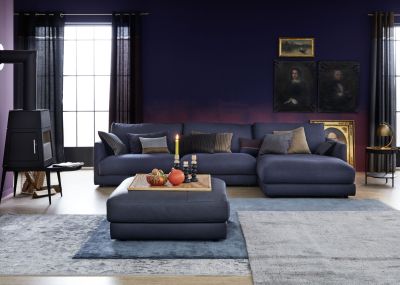 Einrichtungsidee: Dunkelblaue Couch vor violetter Wand auf hellem Fliesenboden.