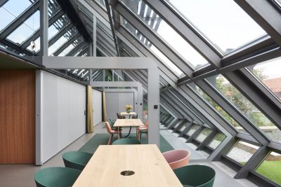 Heller, moderner Raum mit Glasdach, Holztischen und stilvollem Bodenbelag.