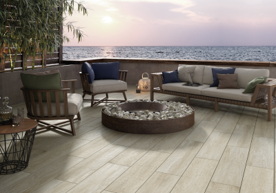 Stilvolle Terrasse mit hellen Outdoor-Fliesen, Feuerstelle und Meerblick.