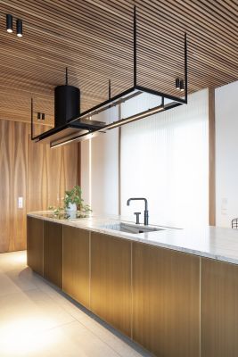 Luxuriöse Küche mit goldener Kücheninsel, Marmorarbeitsplatte, Holzdecke und hellen Bodenfliesen.