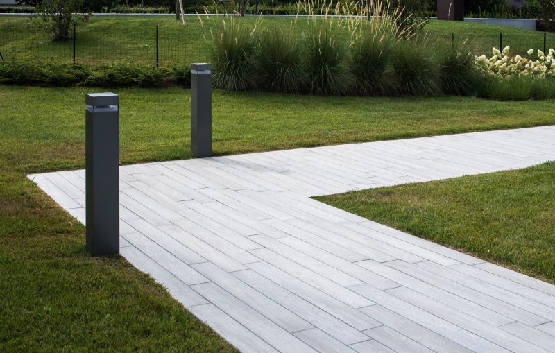 Outdoor-Fliesenweg in Holzoptik mit Rasen und Beleuchtung.