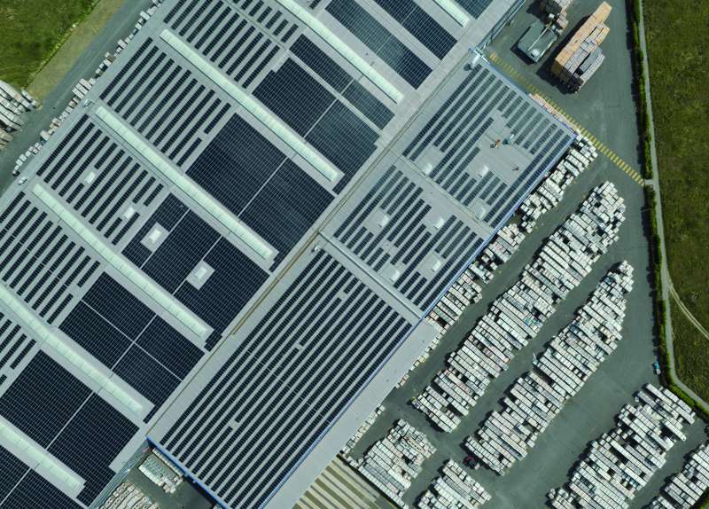 Luftaufnahme einer Fliesenfabrik mit Solarmodulen und gestapelten Fliesenpaletten.