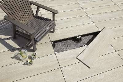 Helle Outdoor-Fliesen auf Stelzlagern, eine Fliese angehoben zeigt die einfache Verlegung.