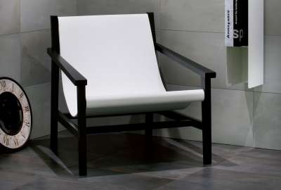 Stilvolles Wohnzimmer mit grauen Porcelaingres Fliesen und modernem Sessel.