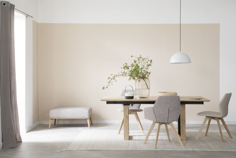 Modernes Esszimmer mit großformatigen hellgrauen Fliesen in Betonoptik, Holztisch und minimalistischer Einrichtung.