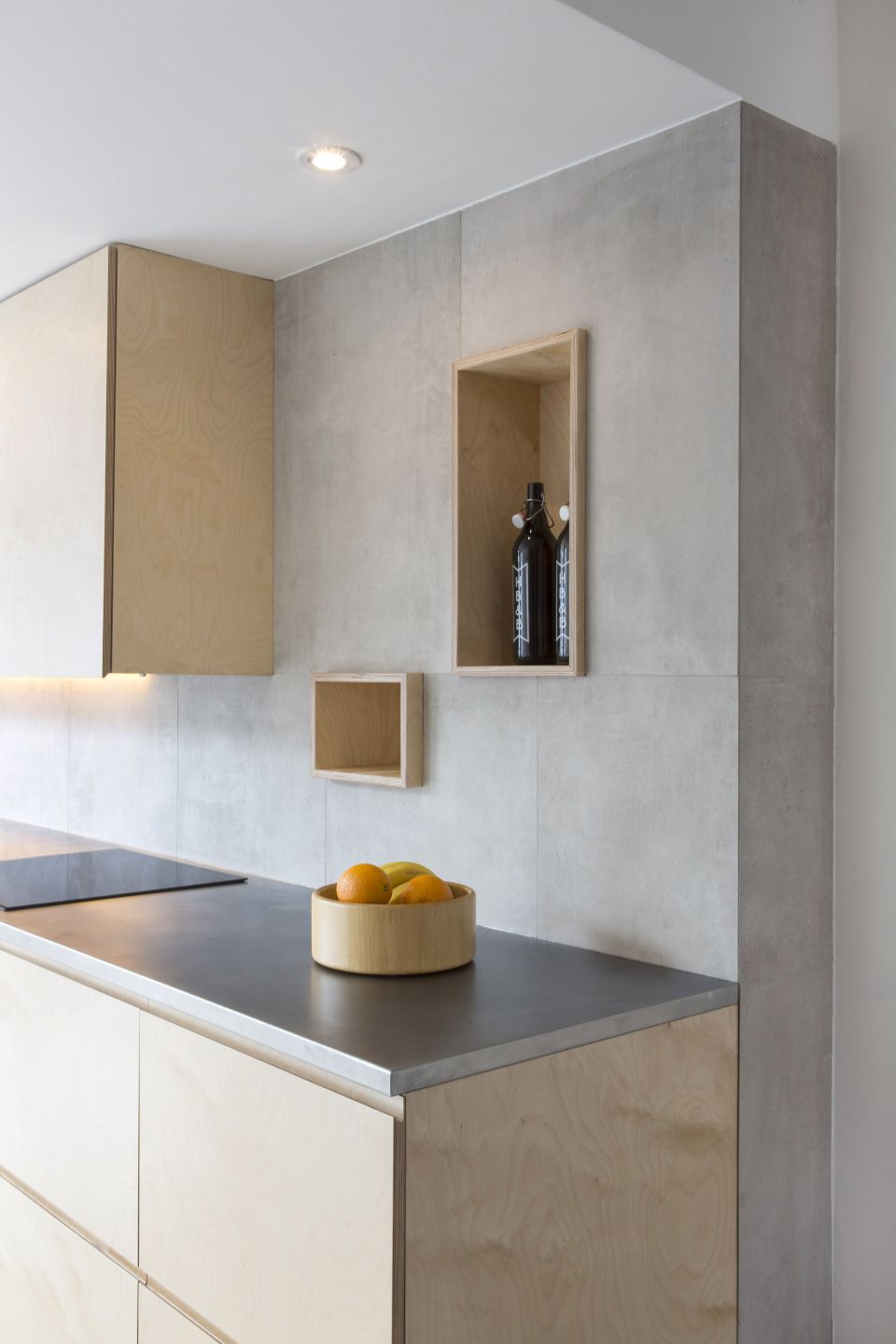 Helle Küche mit großformatigen Fliesen in Betonoptik an der Wand.