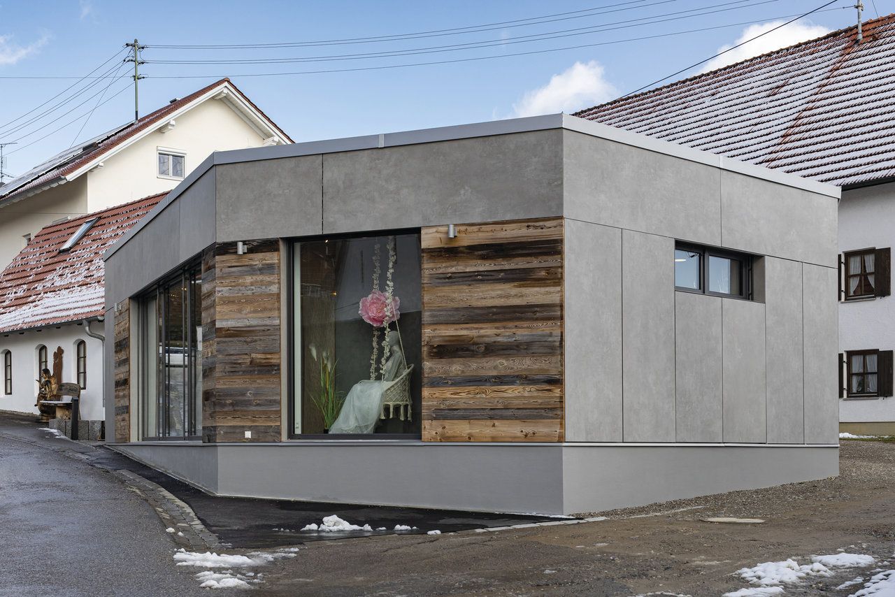 Moderne Fassade mit grauen Platten in Betonoptik und Holzverkleidung.