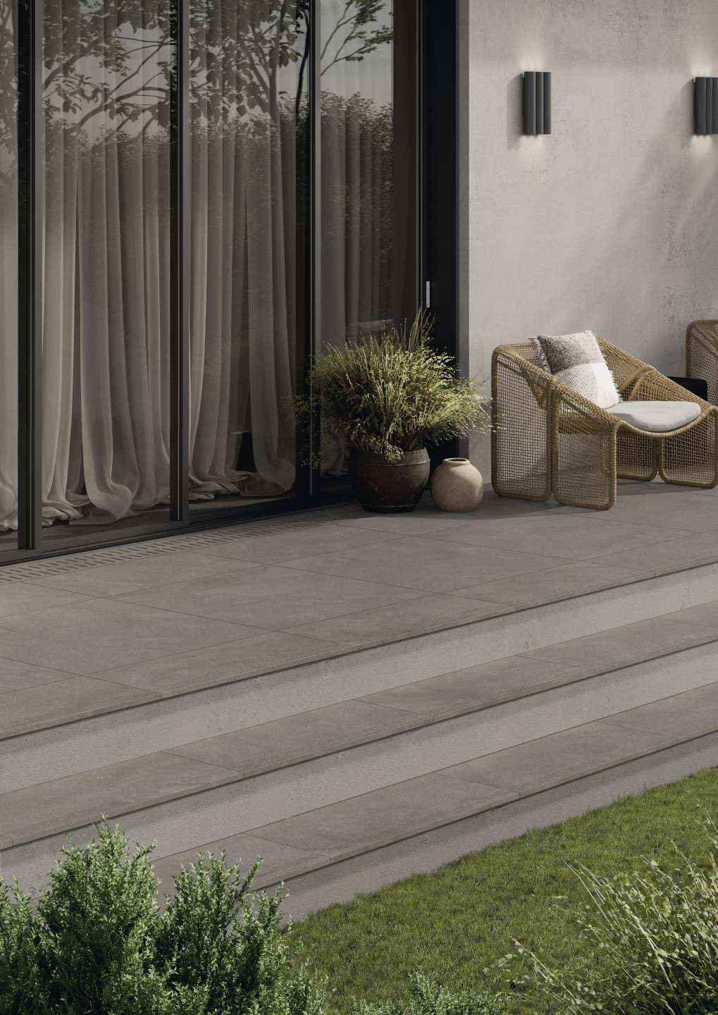 Hochwertige graue Outdoor-Fliesen auf einer modernen Terrasse mit Stufen zum Garten.