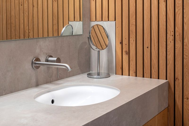 Modernes Bad mit Fliesen in Betonoptik und Holzwand.