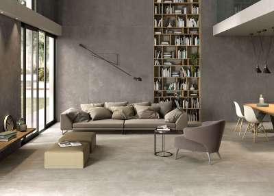Modernes Wohnzimmer mit großformatigen Fliesen an Boden und Wand in eleganter Betonoptik.