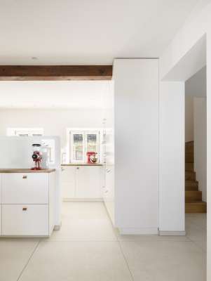 Helle, großformatige Bodenfliesen in moderner Küche und Flur.