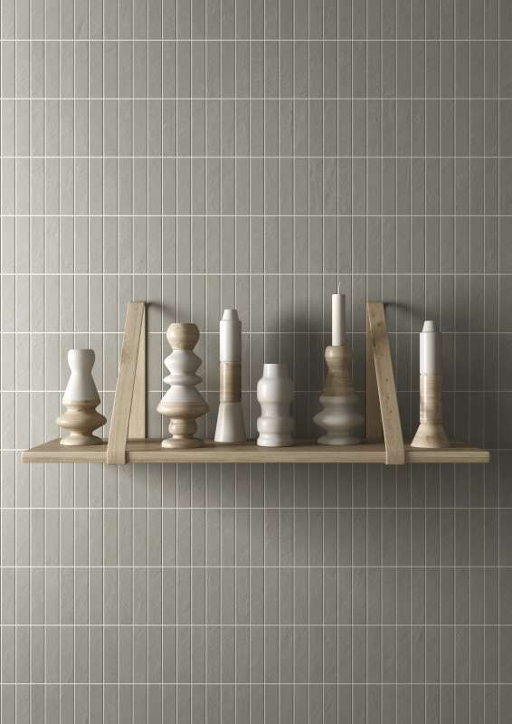 Grüne, vertikal verlegte Wandfliesen als stilvoller Hintergrund für ein Holzregal.