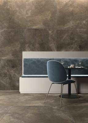 Dunkle Fliesen in Marmoroptik an Wand und Boden eines eleganten Innenraums mit Sitzgelegenheit.