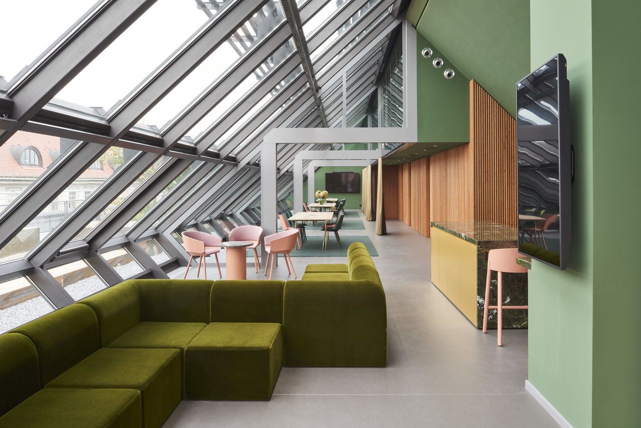 Moderner, heller Raum mit großformatigen Fliesen, grüner Lounge-Ecke und Glasfront.