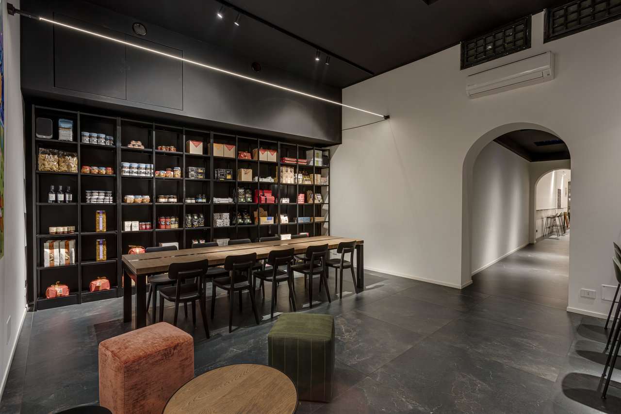 Moderner Showroom mit dunklen Bodenfliesen, langem Tisch und elegantem Wandregal.