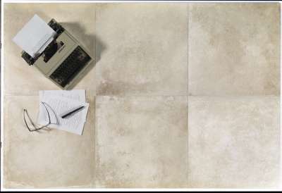 Beigefarbene Bodenfliesen im Used-Look, dekoriert mit einer Schreibmaschine und Brille.