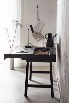 Dunkler, moderner Tisch mit minimalistischer Einrichtung in hellem Raum.